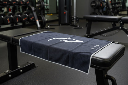 Navy blue towel with a white logo draped over a gym bench.